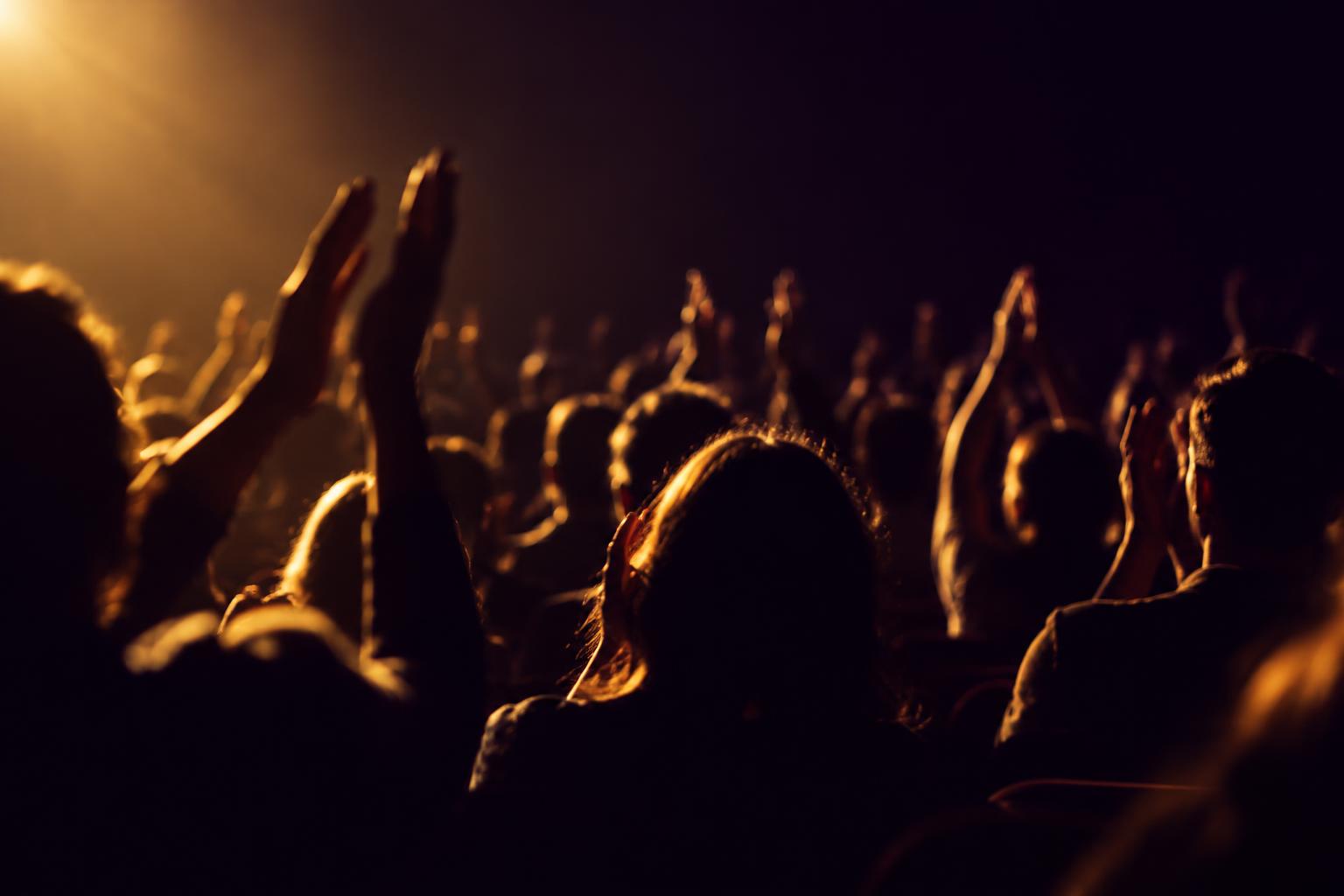 An audience applauding in a darkened theater